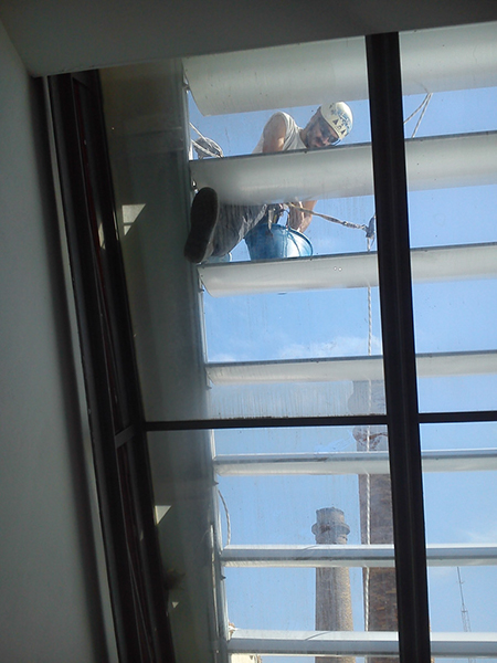 Operario suspendido limpiando los cristales en altura del edificio Palma Activa