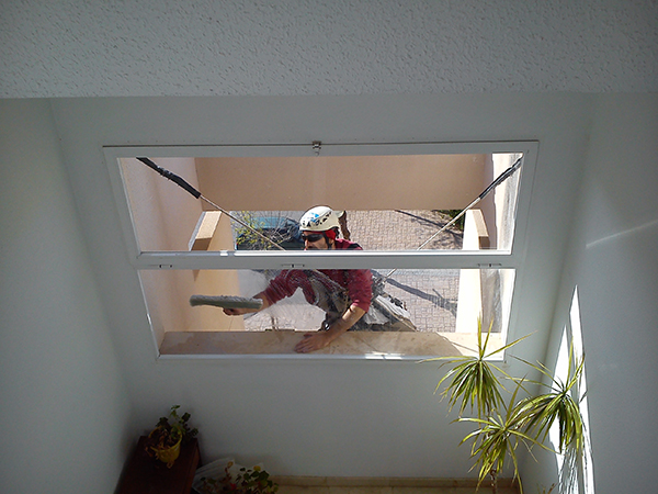 Operario limpiando los ventanales del edificio comunitario