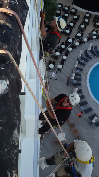 Operario descolgado por la fachada del hotel Edén
